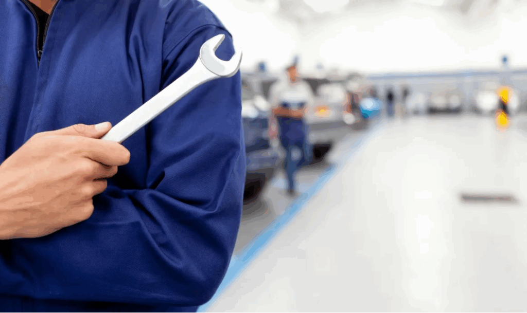 Auto mechanic in blue uniform holding a wrench in repair shop